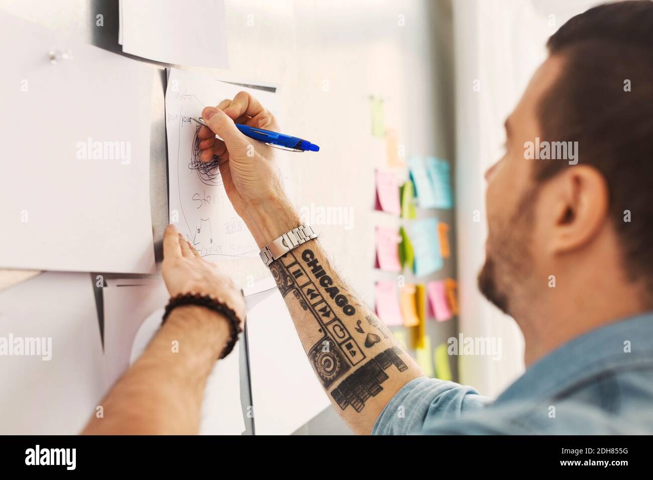 Uomo d'affari medio adulto che scrive su carta in ufficio Foto Stock