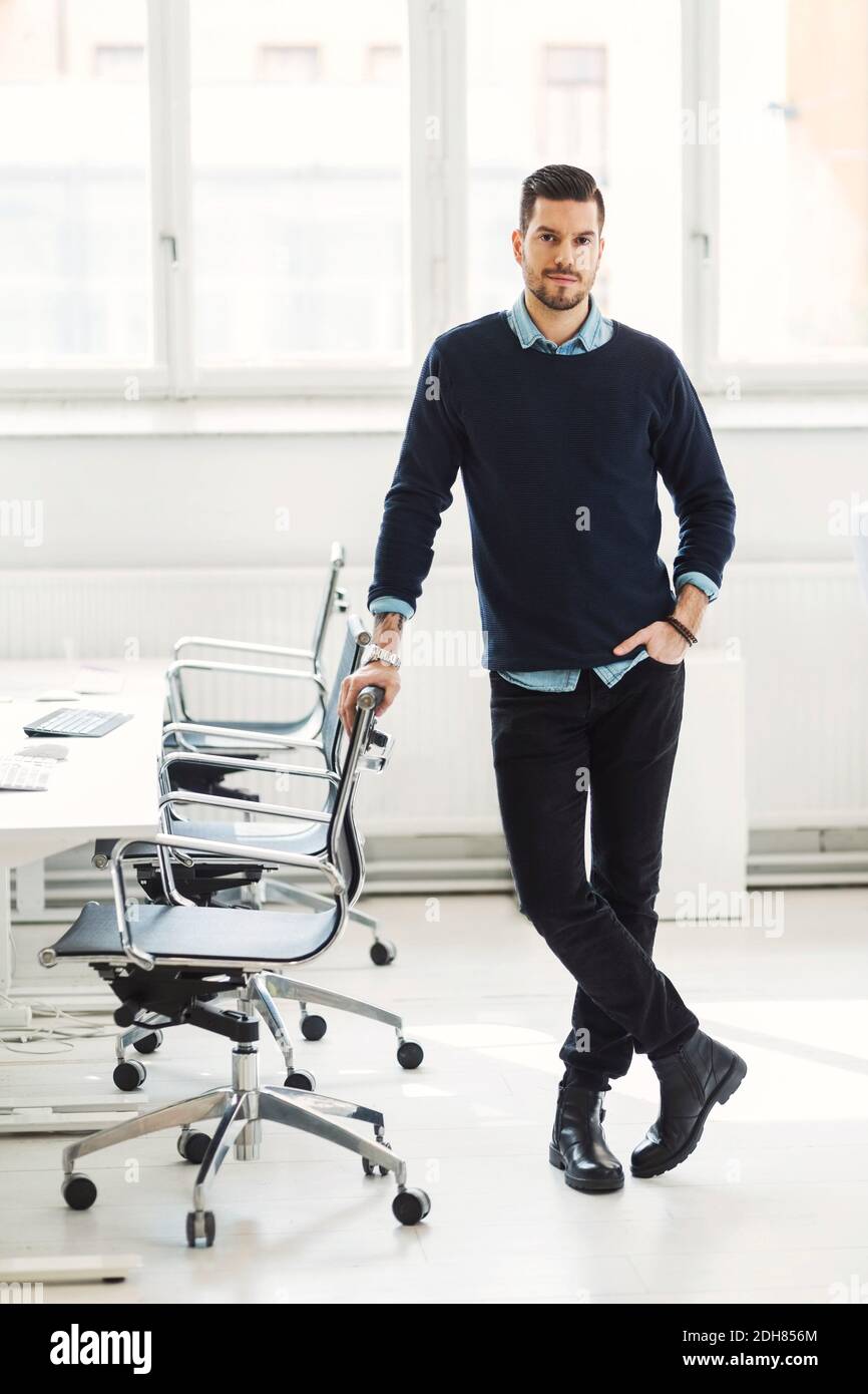Ritratto a lunghezza intera di uomo d'affari sicuro appoggiato sulla sedia da ufficio Foto Stock