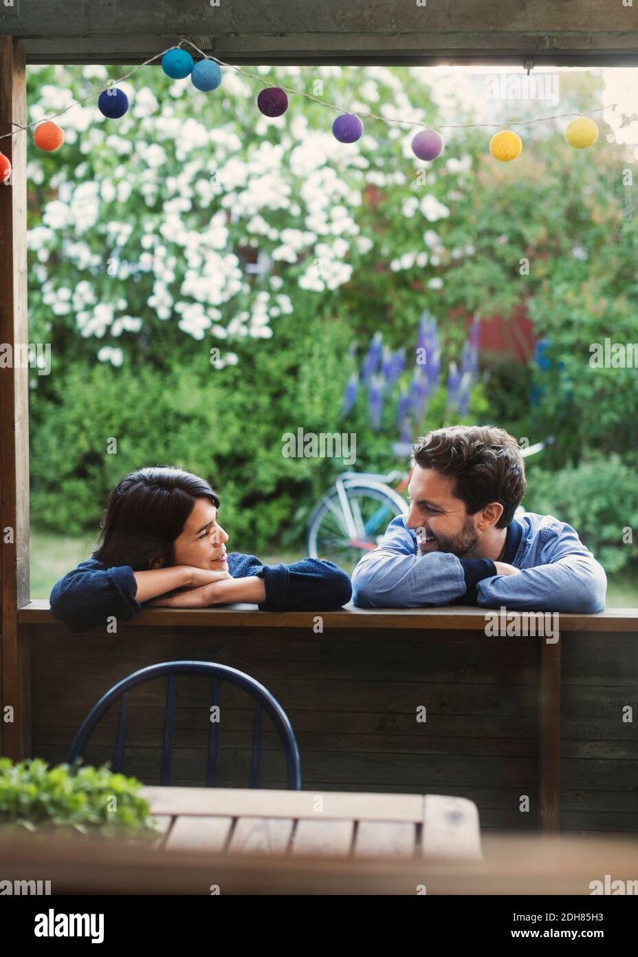 Una coppia sorridente che guarda ciascuno mentre si appoggia su una cabina di legno Foto Stock
