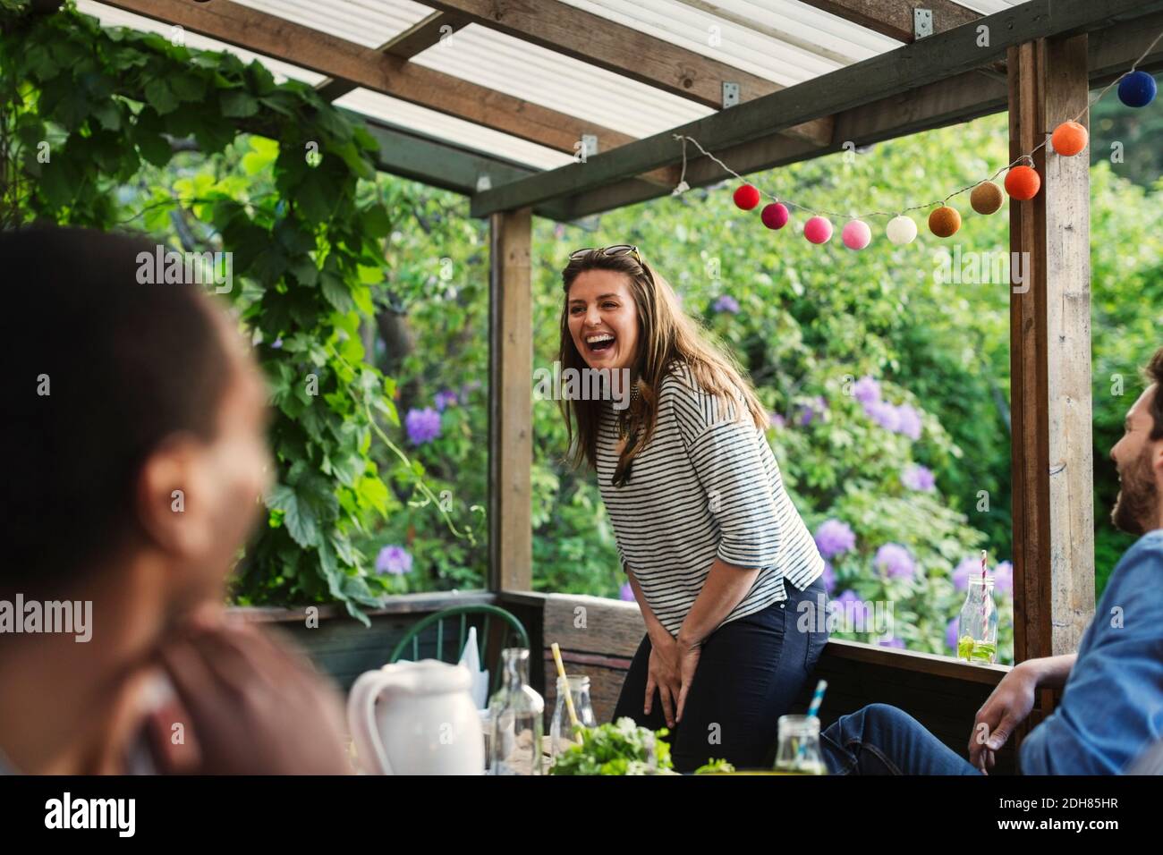 Donna felice che si gode festa con gli amici in casa d'estate Foto Stock