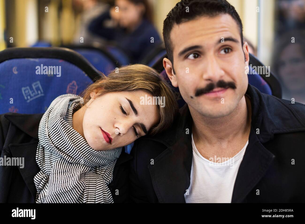 Giovane donna che pende la testa sulla spalla dell'uomo in tram Foto Stock