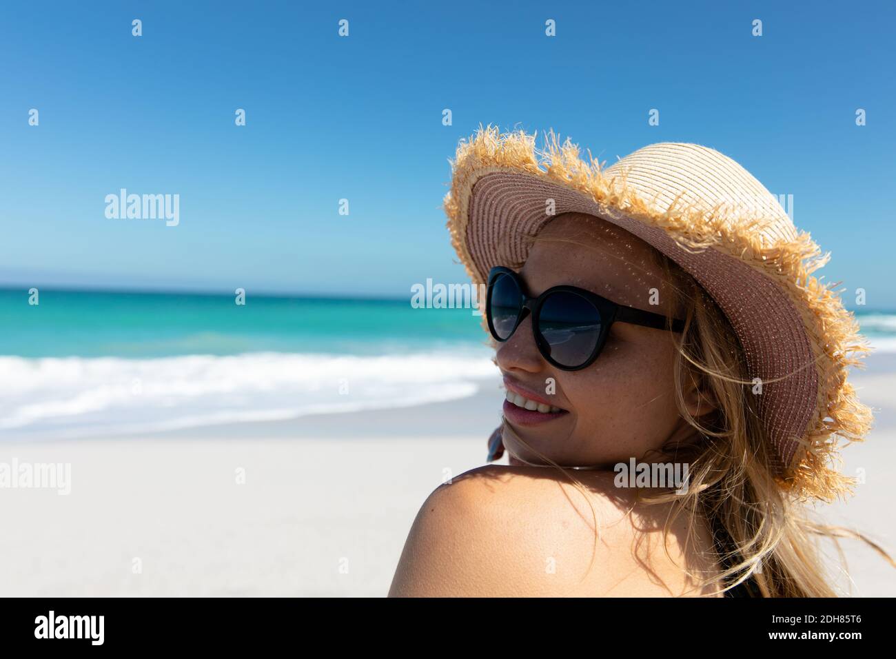 Giovane donna con cappello che sorride in spiaggia Foto stock - Alamy