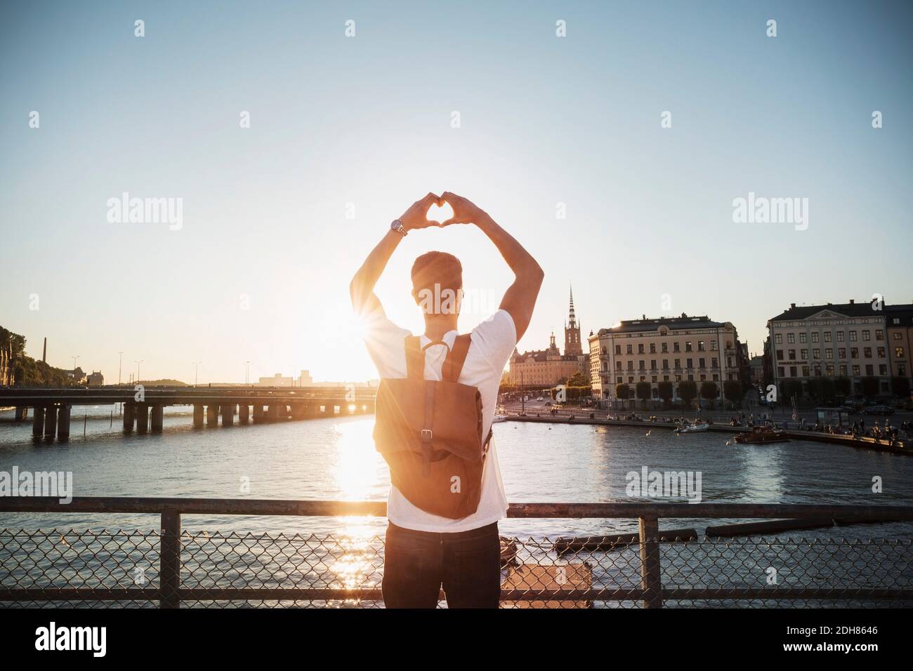 Turista maschile facendo forma del cuore con le mani in città contro cielo limpido Foto Stock