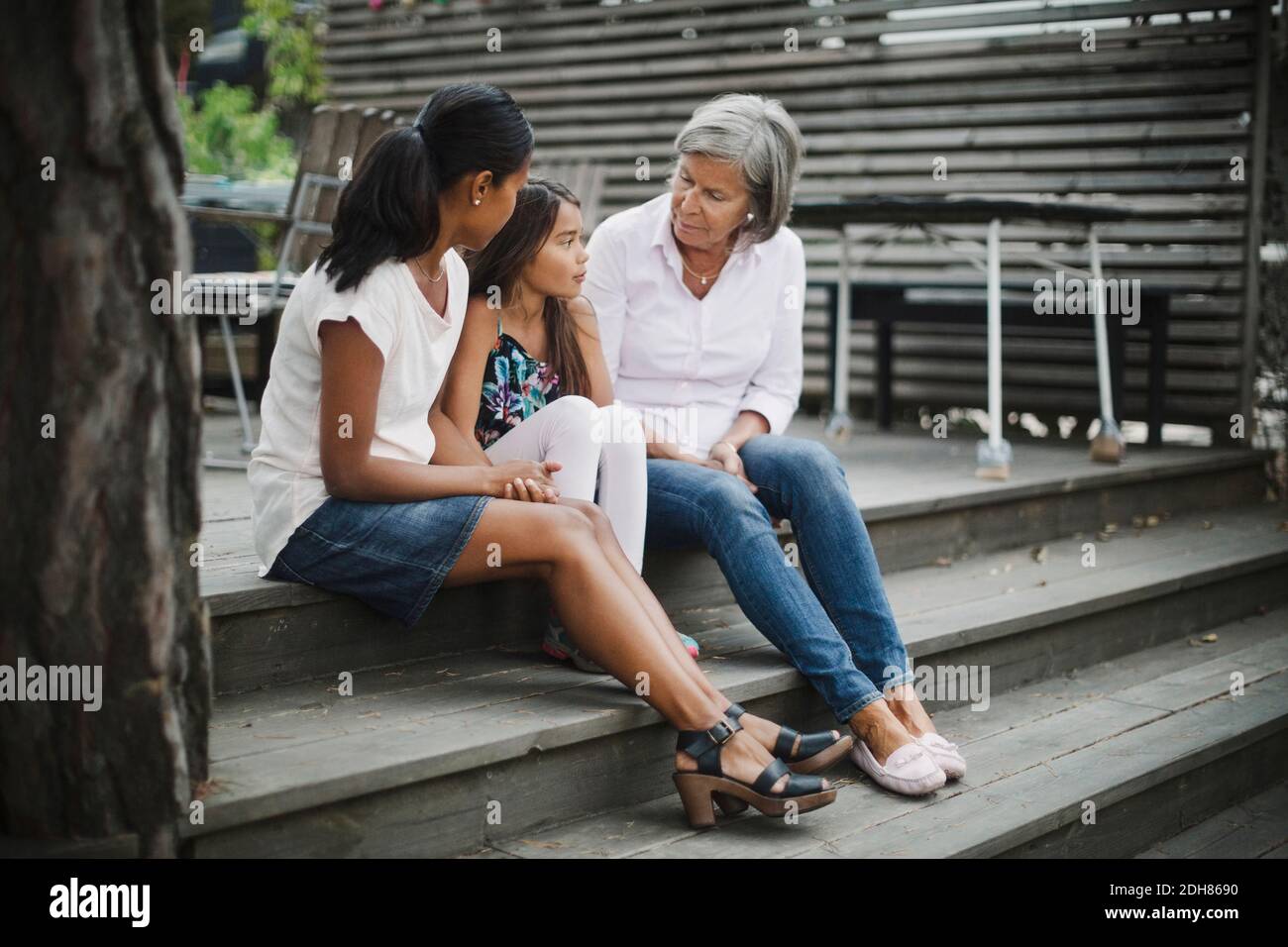 Tre donne di generazione che siedono sui gradini al cortile Foto Stock