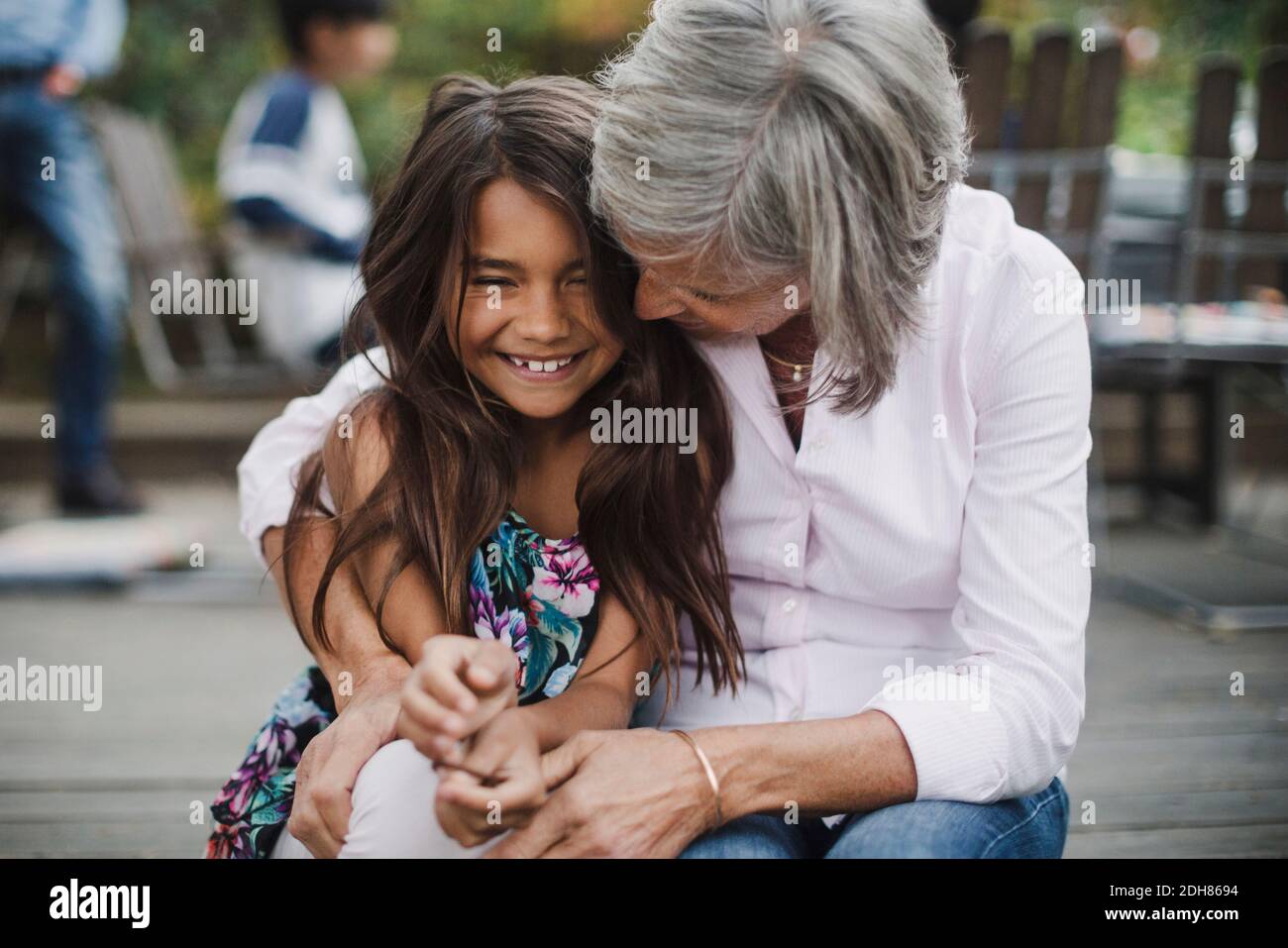 Donna anziana che abbraccia la nipote mentre si siede in cortile Foto Stock