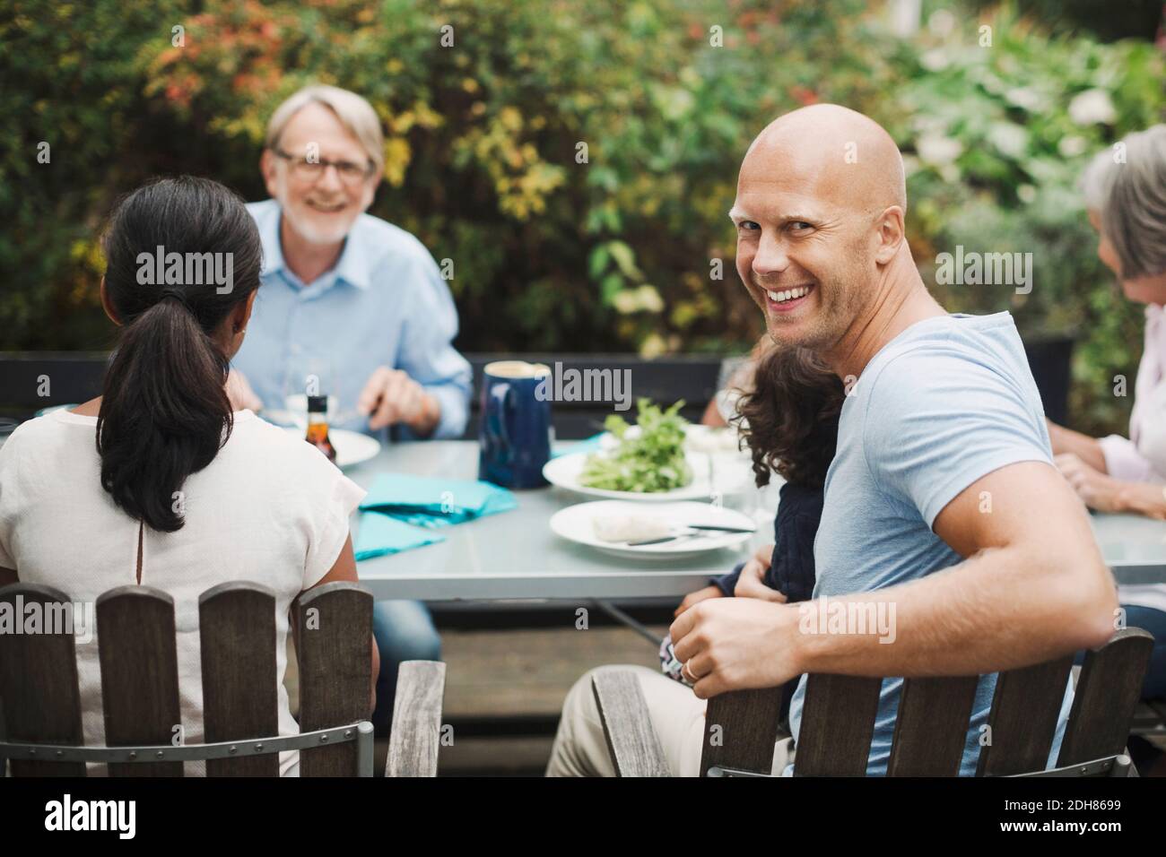 Vista laterale ritratto di felice uomo godendo pasto con la famiglia al tavolo esterno Foto Stock