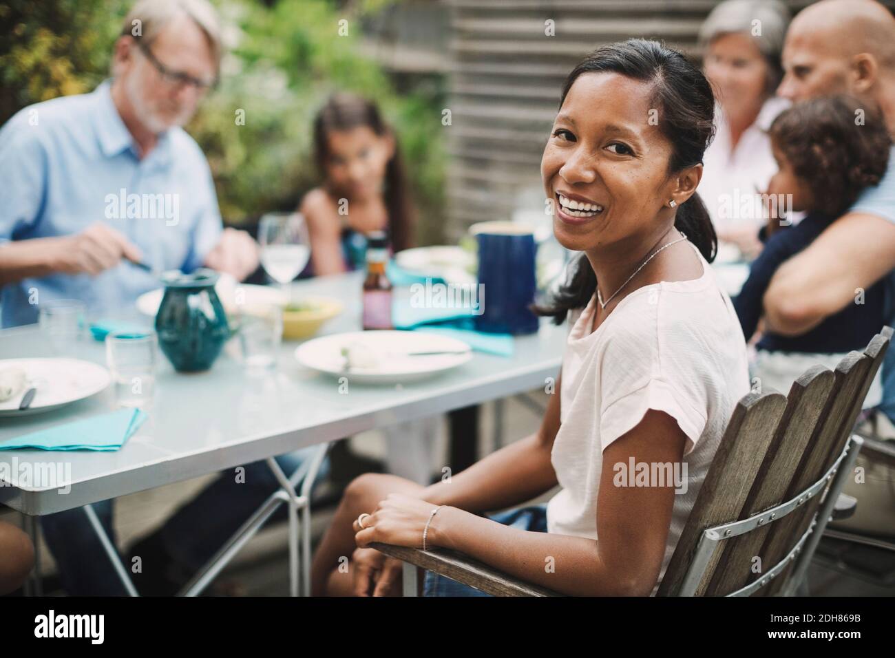 Ritratto di donna felice seduta con la famiglia al ristorante all'aperto tabella Foto Stock