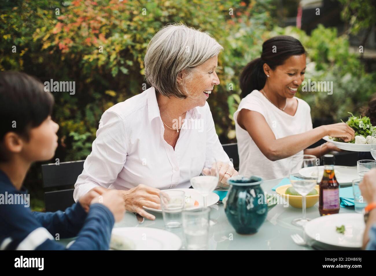 Buona famiglia che mangiano al tavolo in cortile Foto Stock