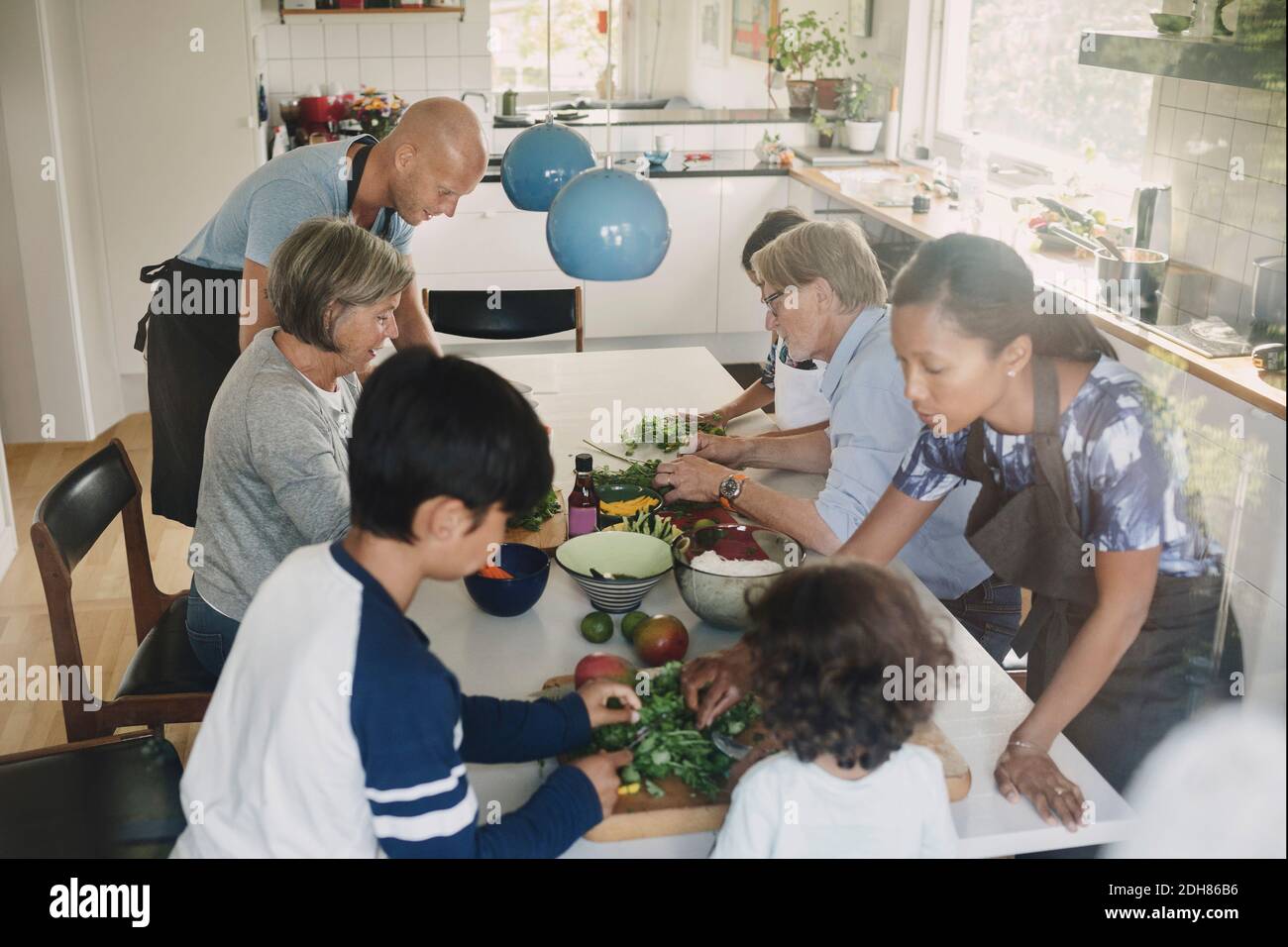Vista ad alto angolo della famiglia che prepara piatti asiatici al tavolo Foto Stock