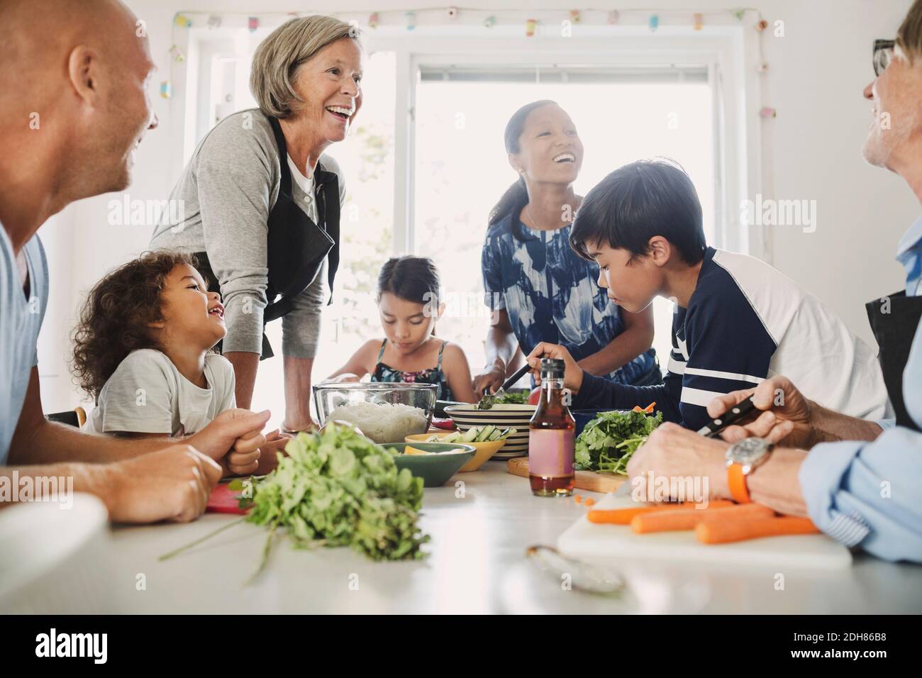 Felice famiglia multietnica che prepara cibo asiatico in cucina Foto Stock