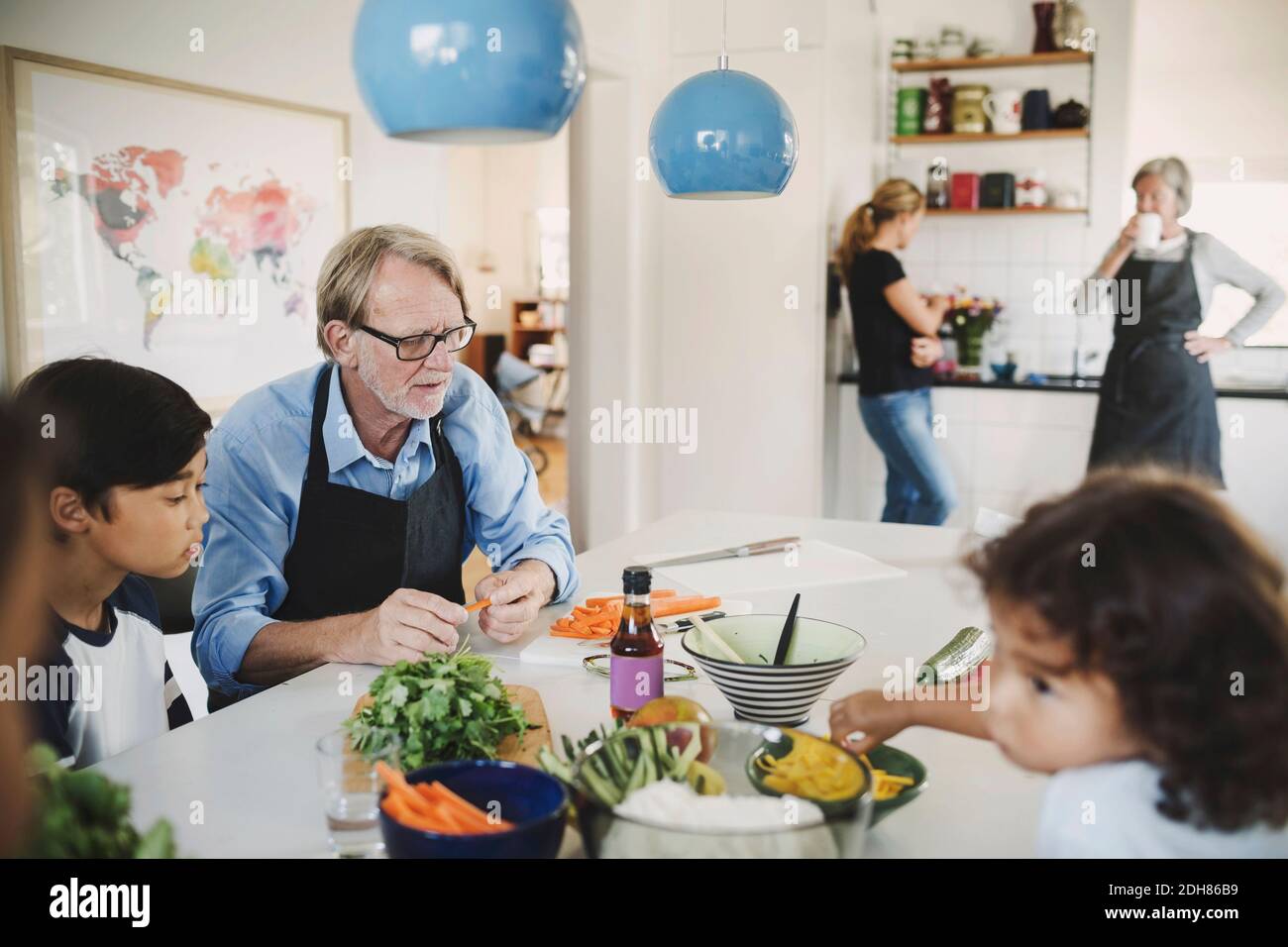 Nonno e bambini che preparano il cibo in cucina Foto Stock