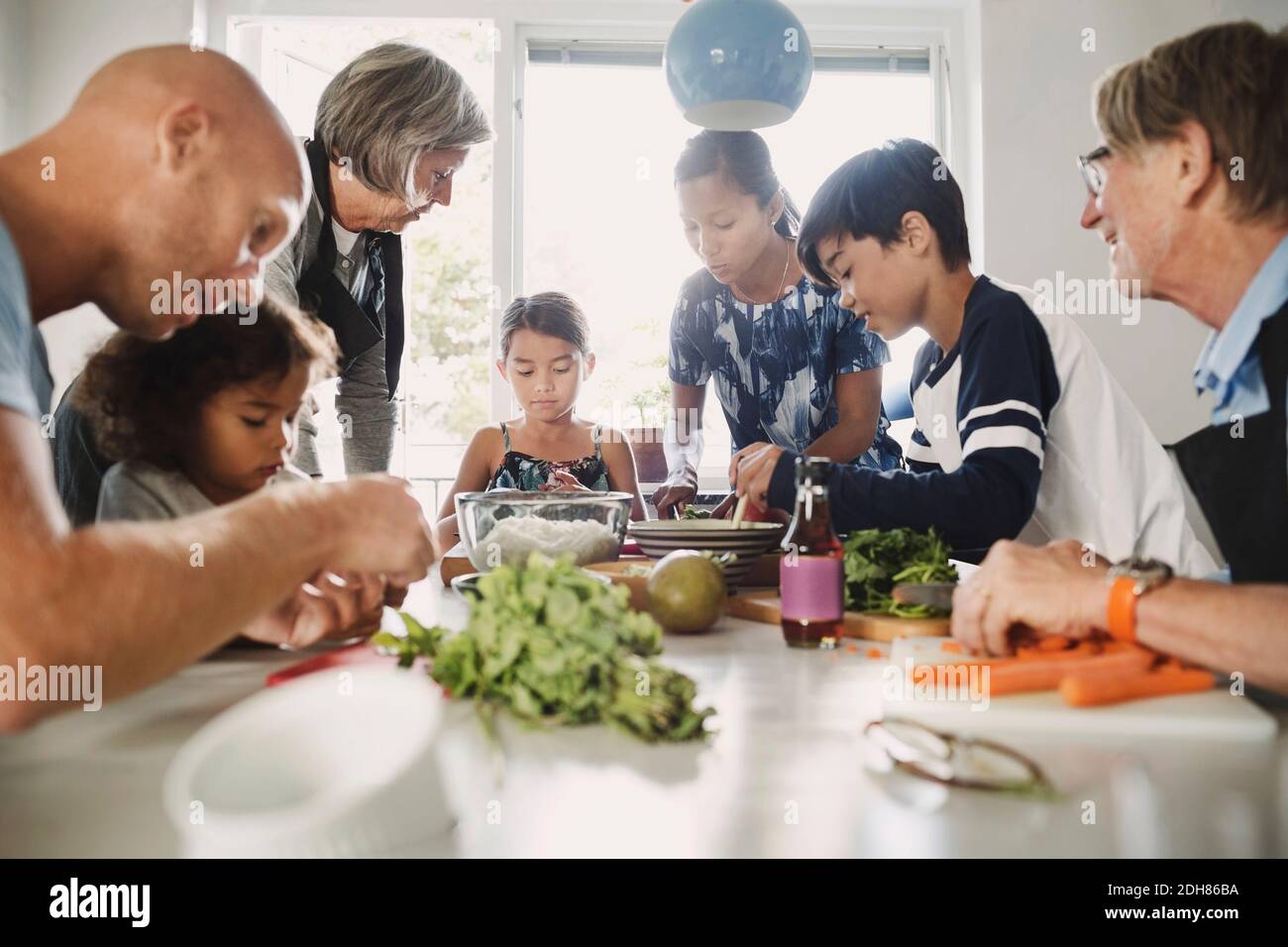 Famiglia multietnica che prepara cibo asiatico in cucina Foto Stock
