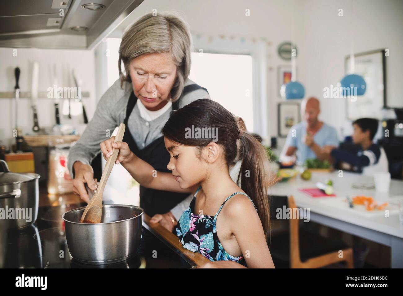 Nonna che guarda la ragazza che cucinano al banco della cucina Foto Stock