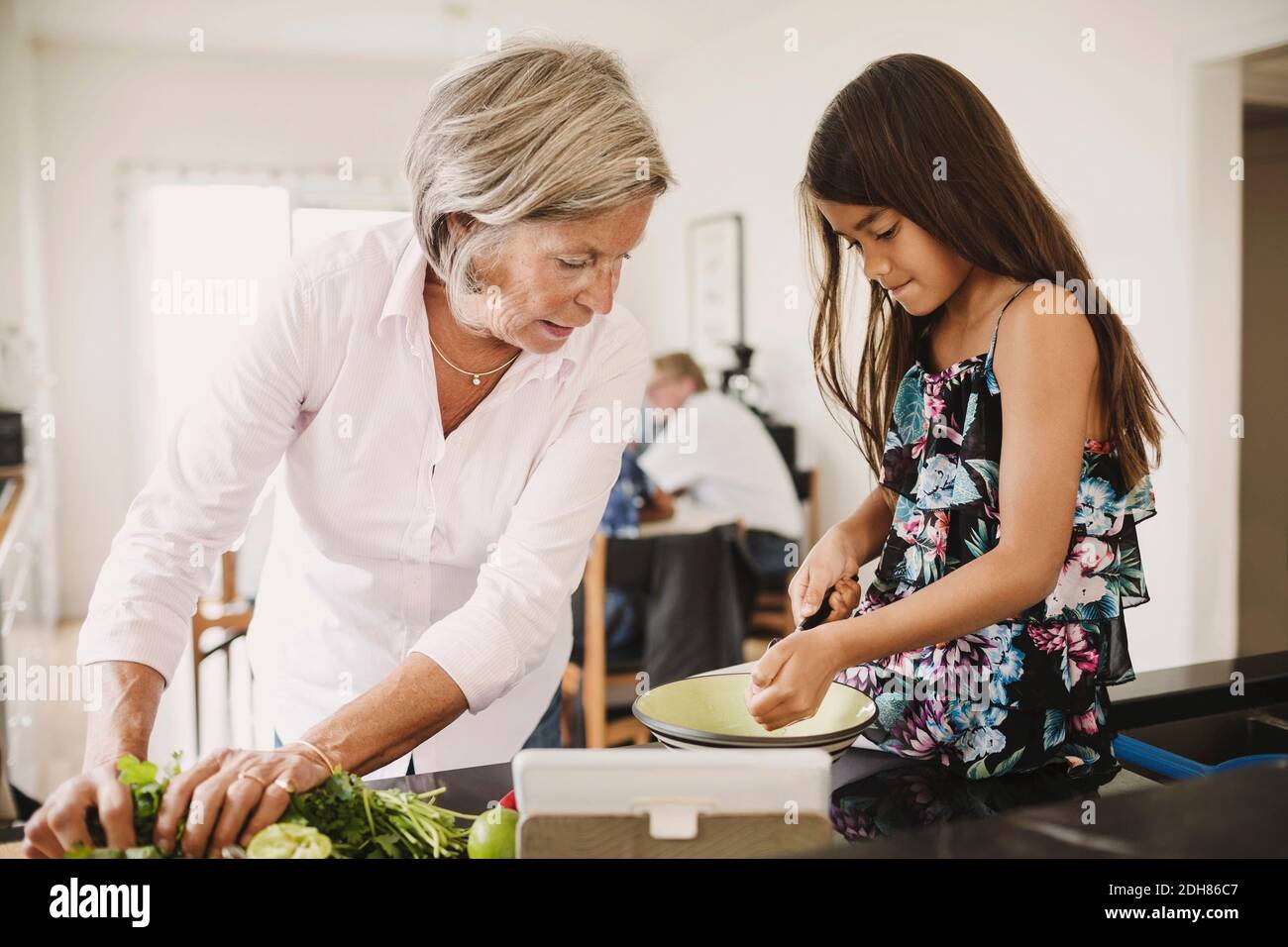 Nipote e nonna preparano il cibo in cucina Foto Stock
