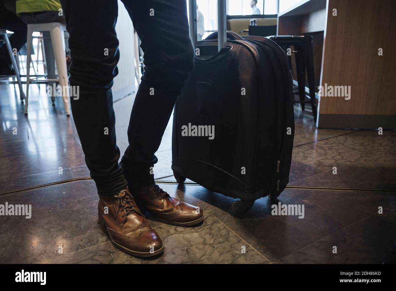 Una sezione bassa di uomini d'affari in piedi con bagagli su ruote all'aeroporto Foto Stock