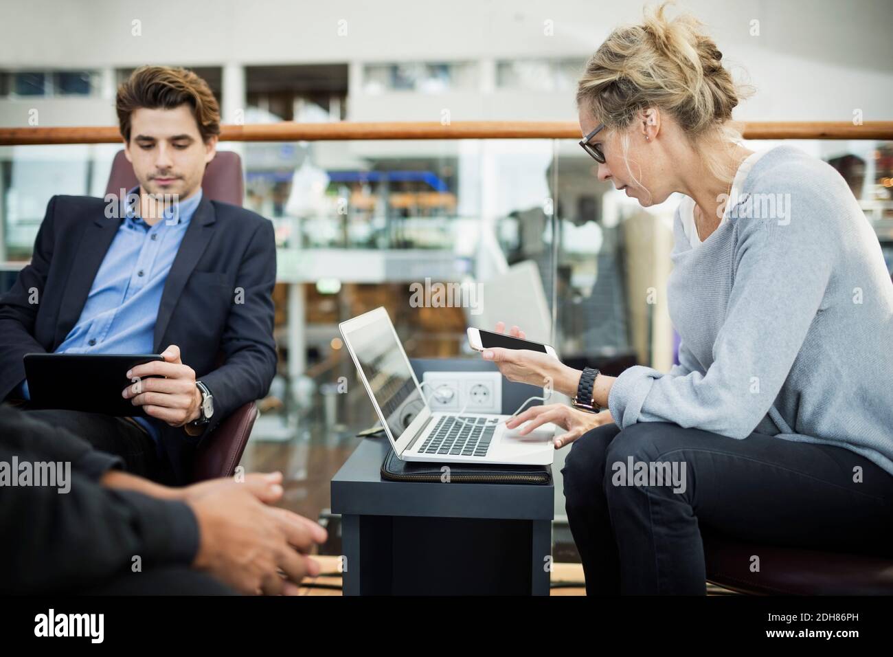 Uomini d'affari che utilizzano tecnologie nella lobby dell'aeroporto Foto Stock