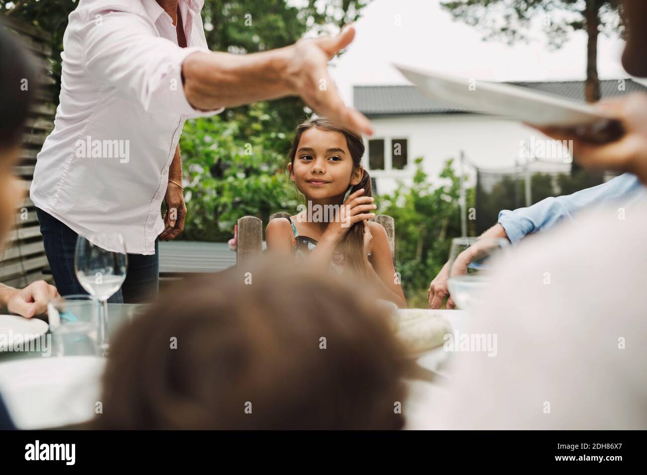 Sezione centrale della donna anziana che prende il piatto dalla nuora all'aperto tavolo da pranzo Foto Stock
