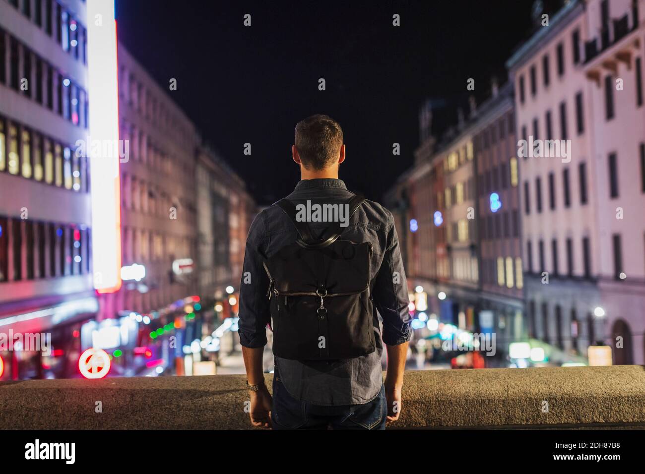 Vista posteriore dello zaino da trasporto uomo in piedi sul ponte città di notte Foto Stock