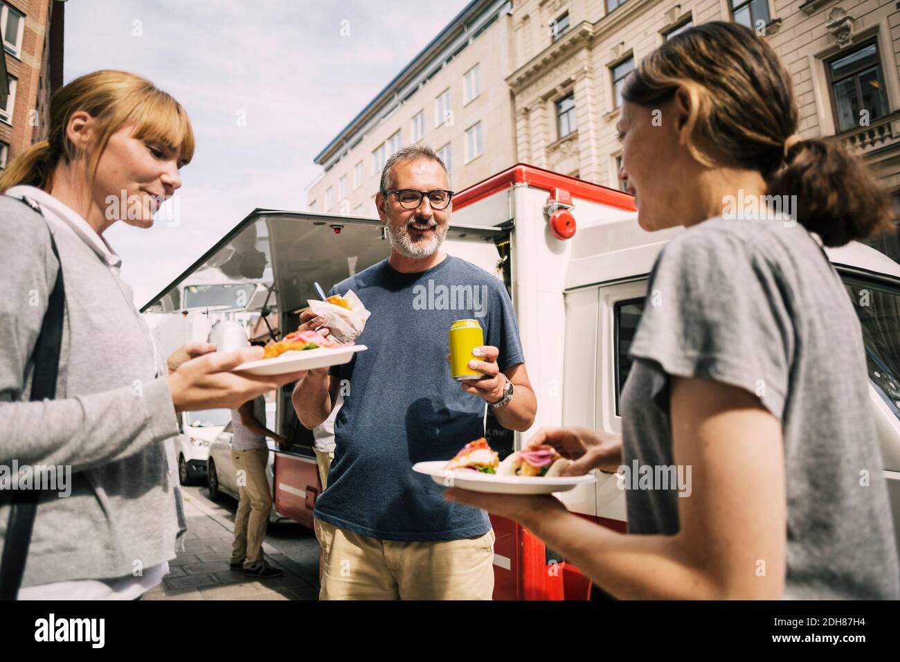 Le persone mangiano spuntini mentre si levano in piedi contro il camion in città Foto Stock