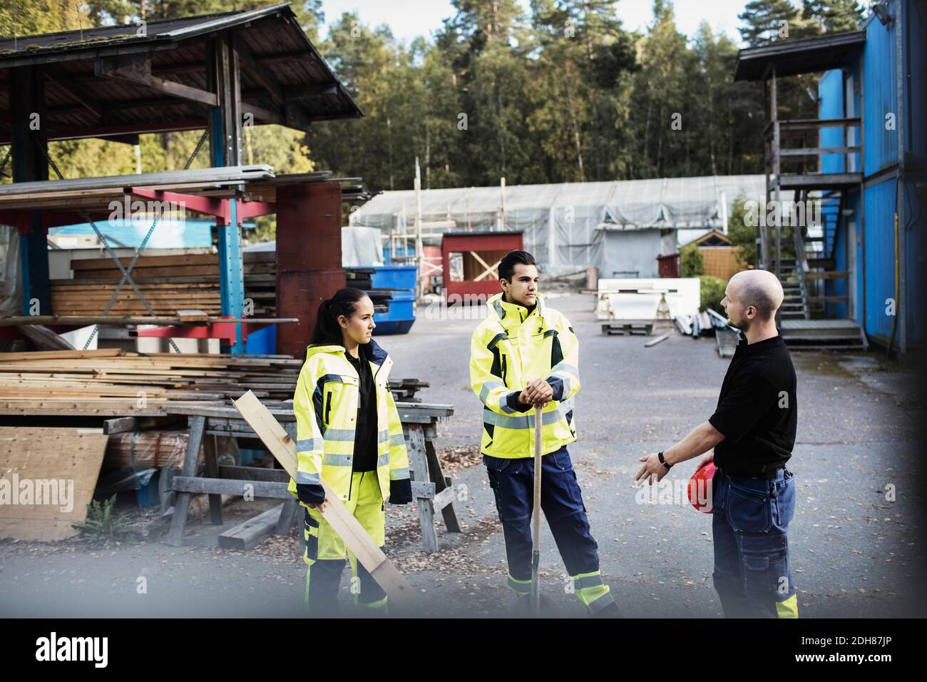 Insegnante che parla con studenti di carpenteria fuori della scuola Foto Stock