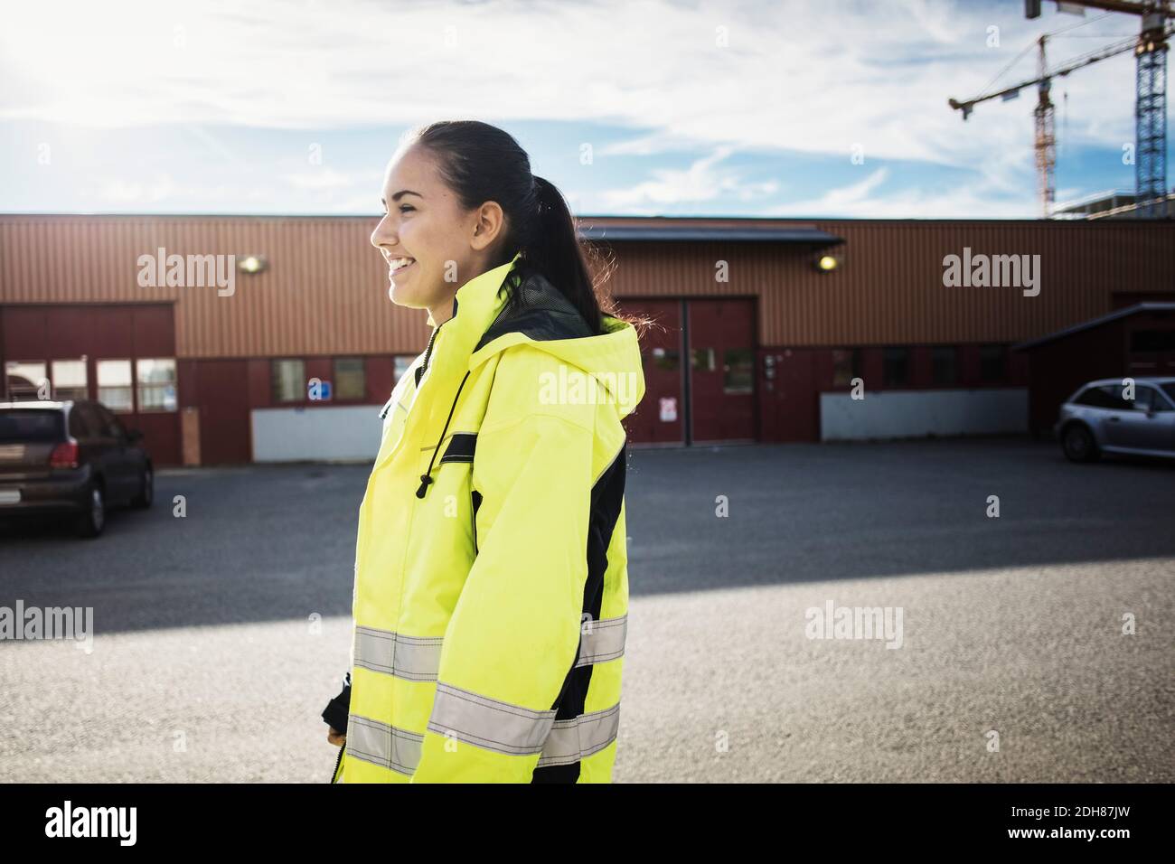 Vista laterale di una studentessa di riparazione auto in piedi fuori dalla scuola Foto Stock