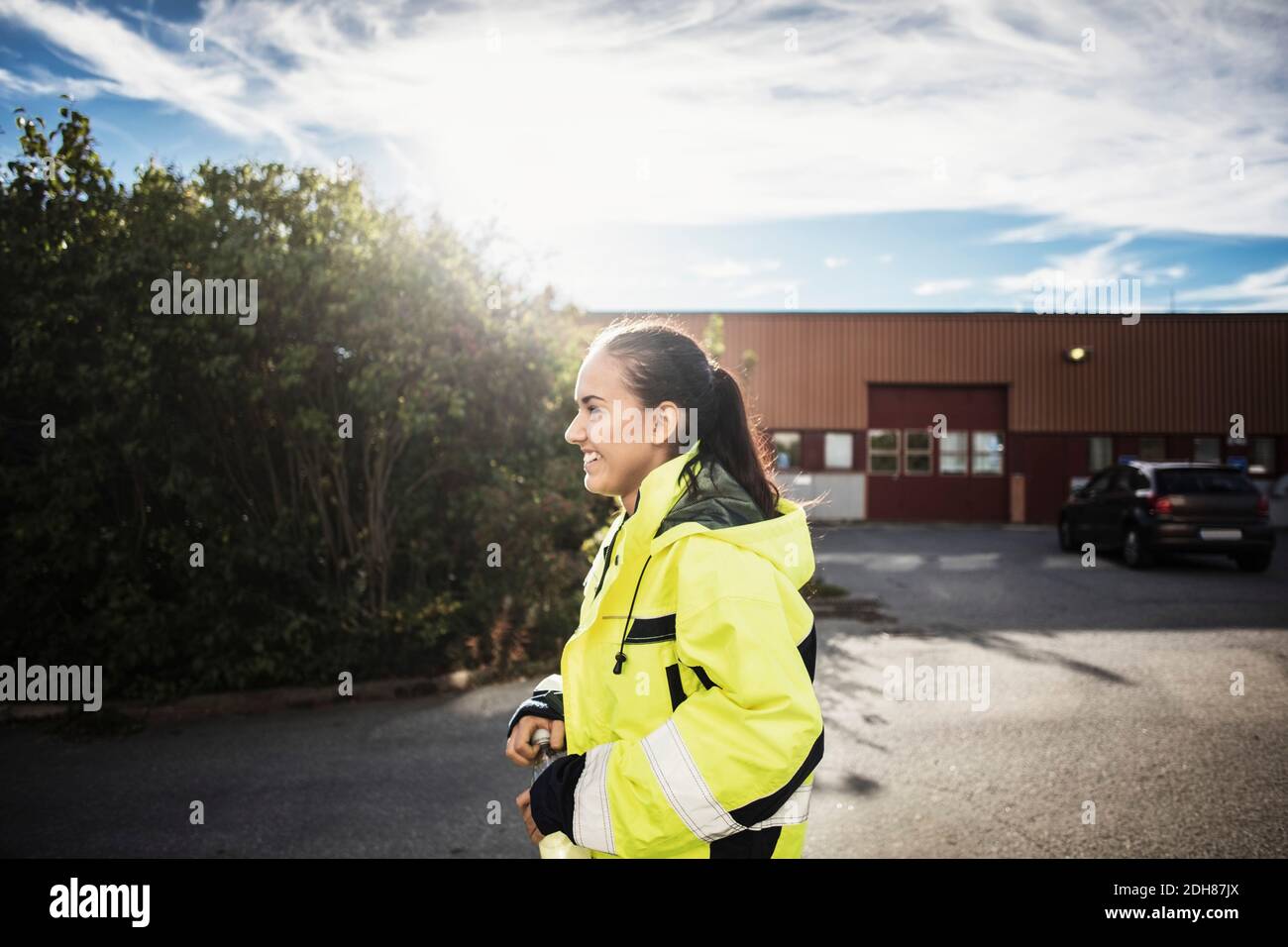 Vista laterale di felice femmina auto riparazione studente che cammina all'esterno scuola Foto Stock