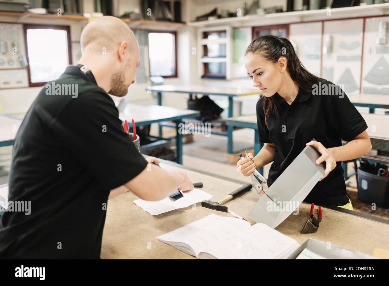 Insegnante di sesso maschile che assiste gli studenti delle scuole superiori sul progetto in classe Foto Stock