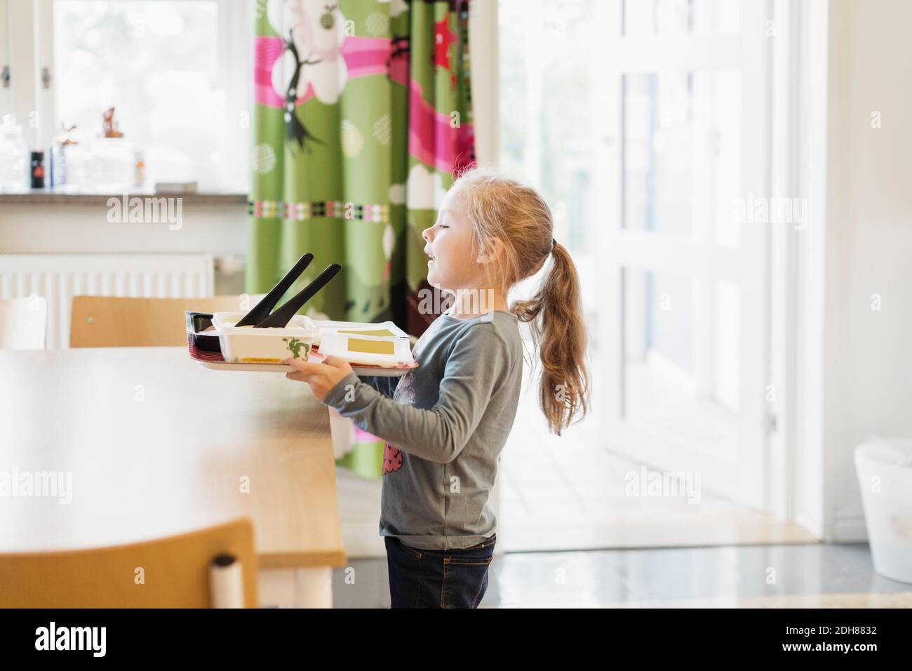 Ragazza che porta vassoio di cibo in prescolare Foto Stock