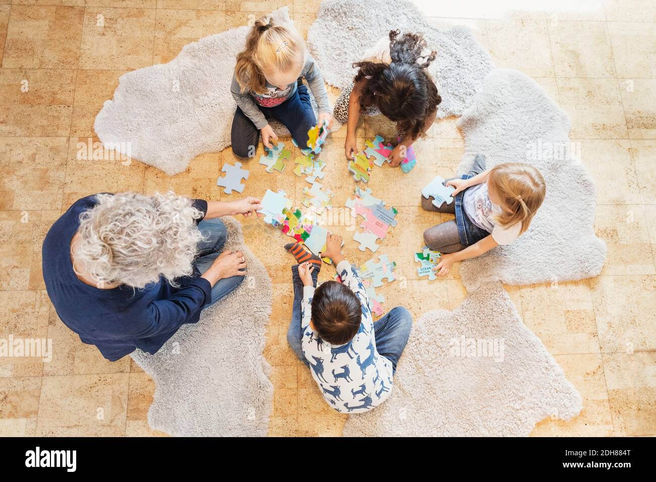 Vista ad alto angolo di insegnante e bambini che giocano puzzle Foto Stock