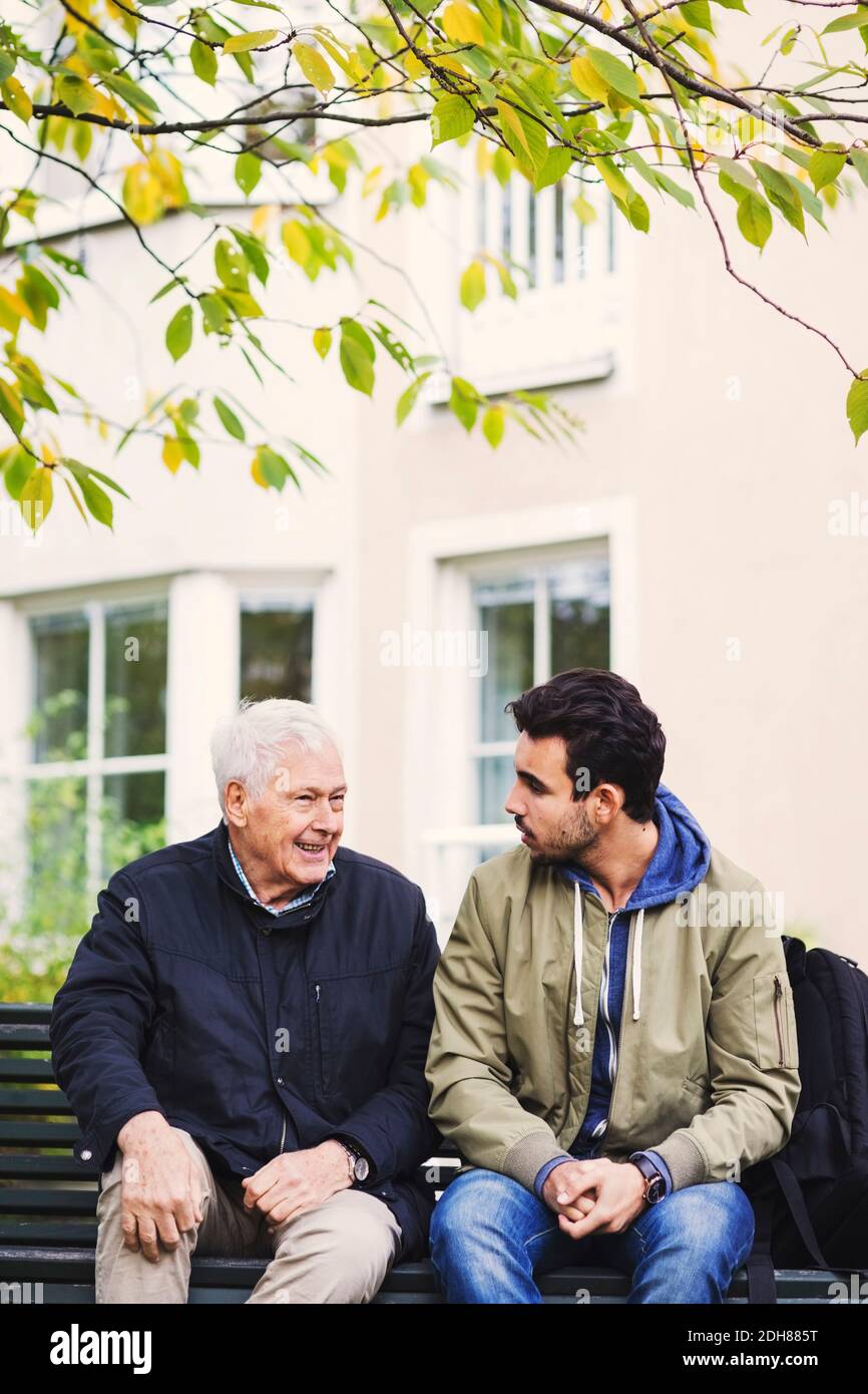 Un custode che comunica con l'uomo anziano mentre si siede sulla panchina Foto Stock