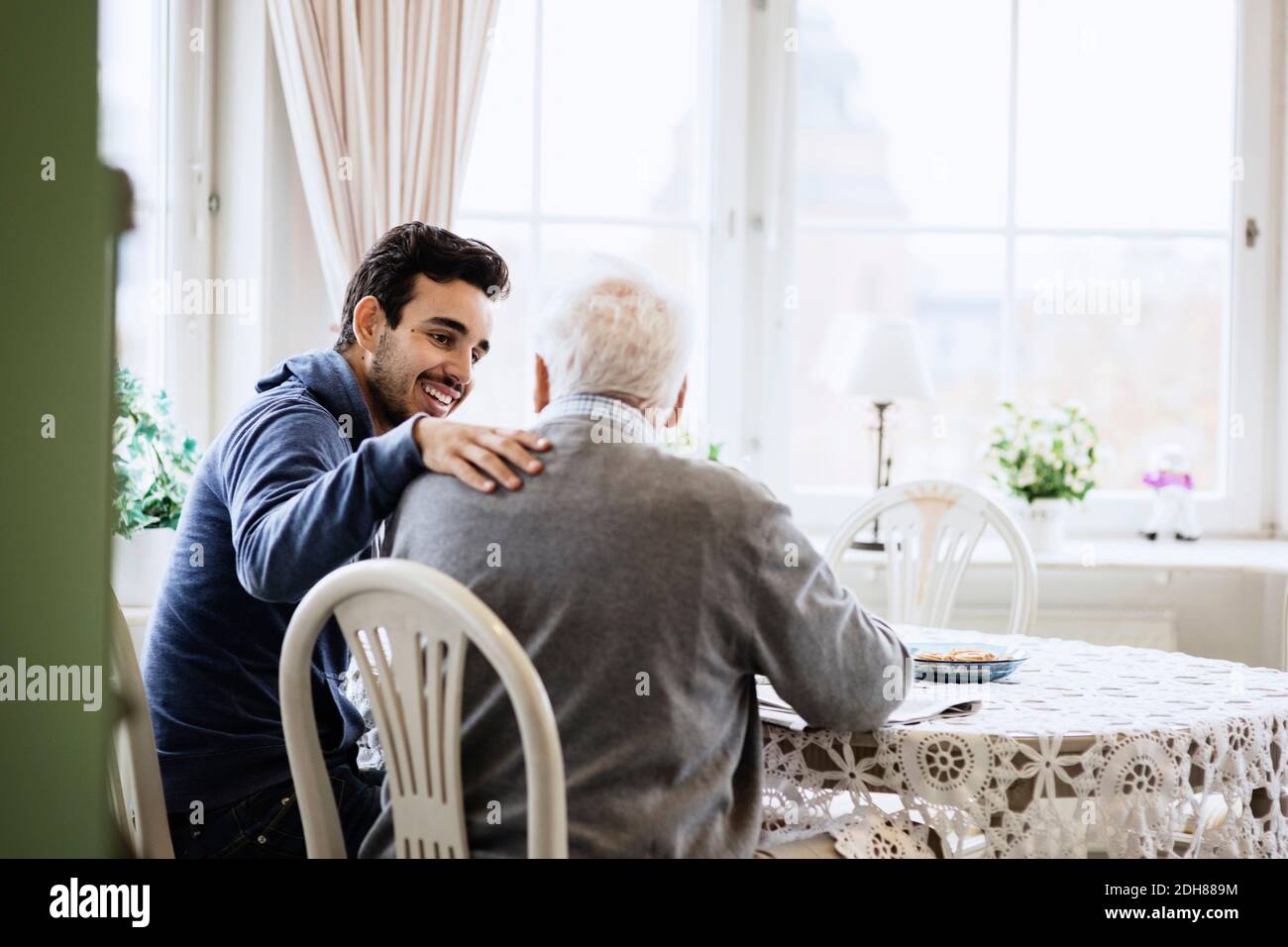 Felice custode che comunica con l'uomo anziano in casa di cura Foto Stock