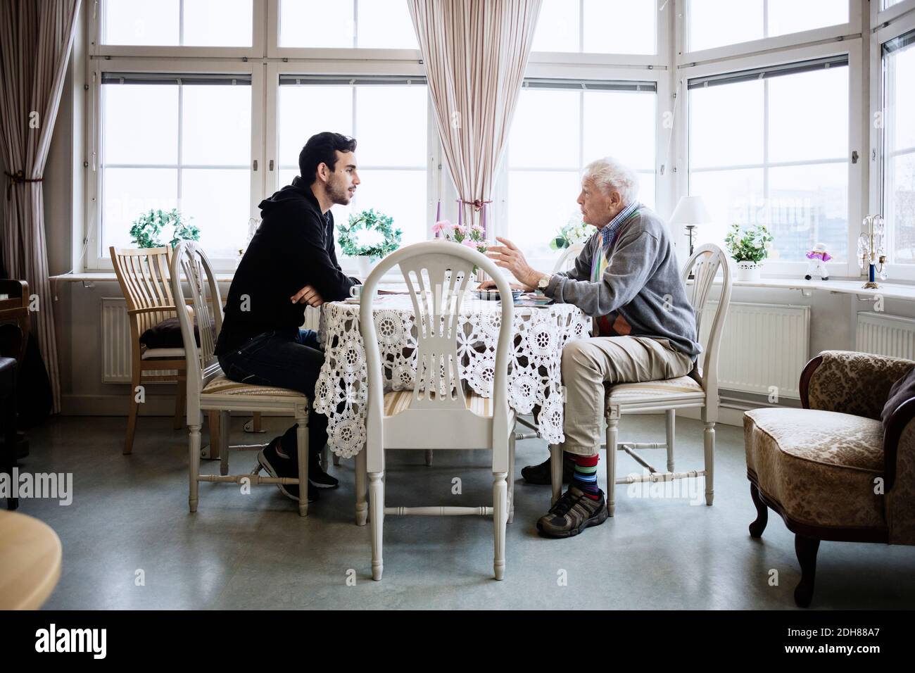 Vista laterale dell'uomo che comunica con il custode al tavolo da pranzo Foto Stock