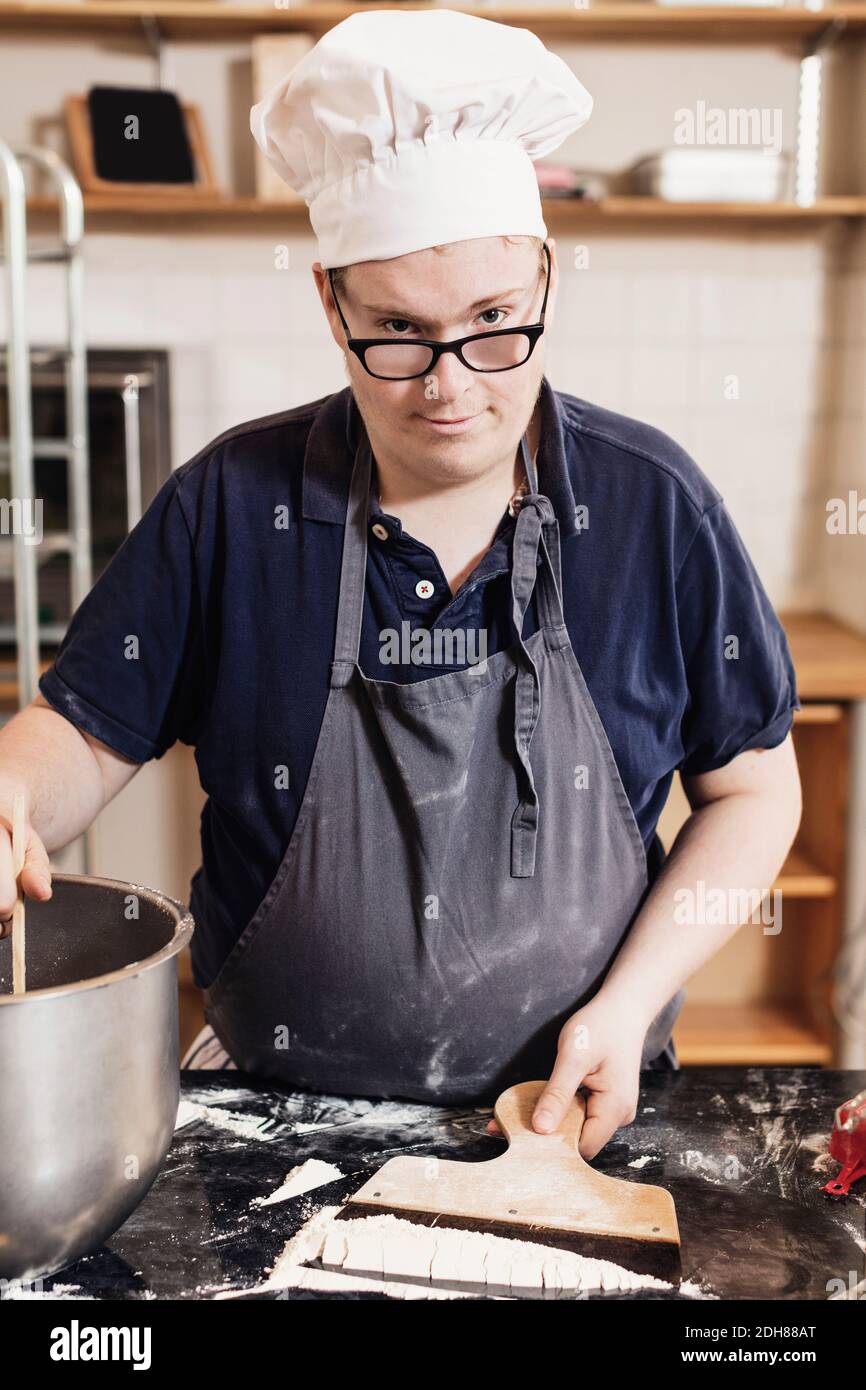 Ritratto di giovane che fa l'impasto in cucina commerciale Foto Stock