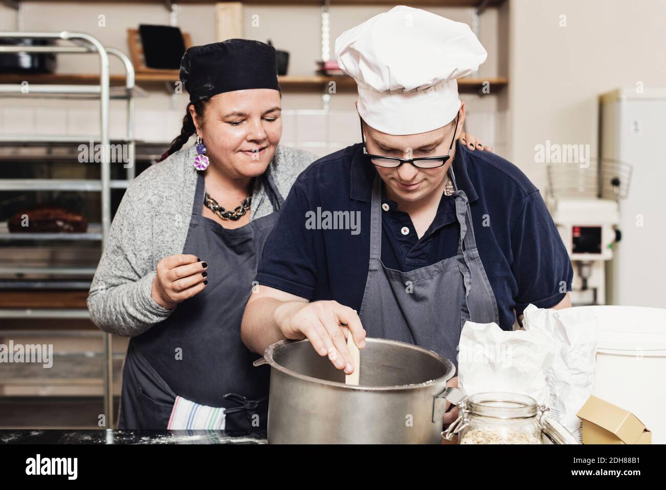 Panettiere maturo che aiuta il collaboratore in cucina alla cucina commerciale Foto Stock