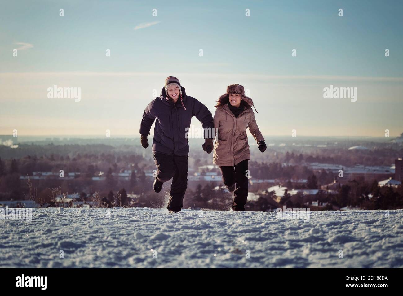 Intera lunghezza di coppia felice che corre sulle montagne innevate Foto Stock