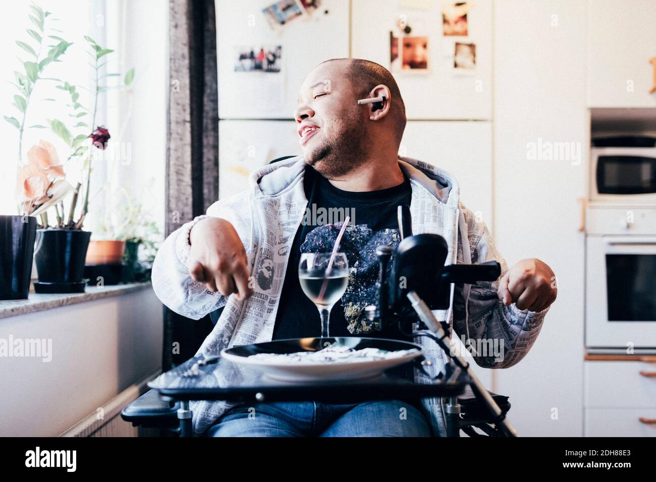 Felice musicista disabile con drink seduto alla finestra di registrazione studio Foto Stock