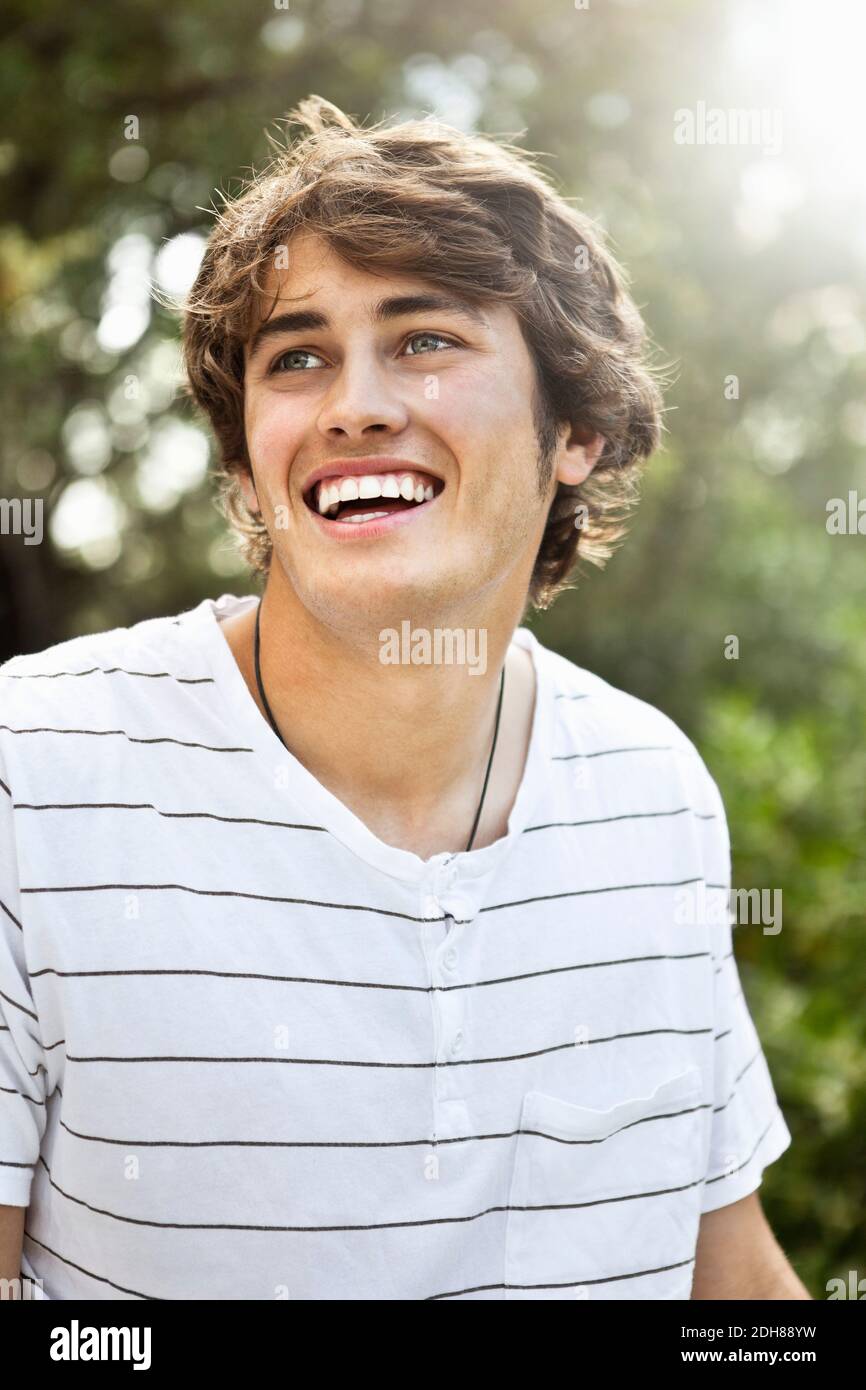 Primo piano di un giovane sorridente che guarda via Foto Stock