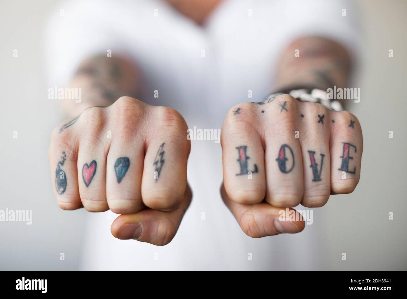Sezione centrale di un uomo che mostra tatuaggi d'amore sui suoi pugni Foto Stock