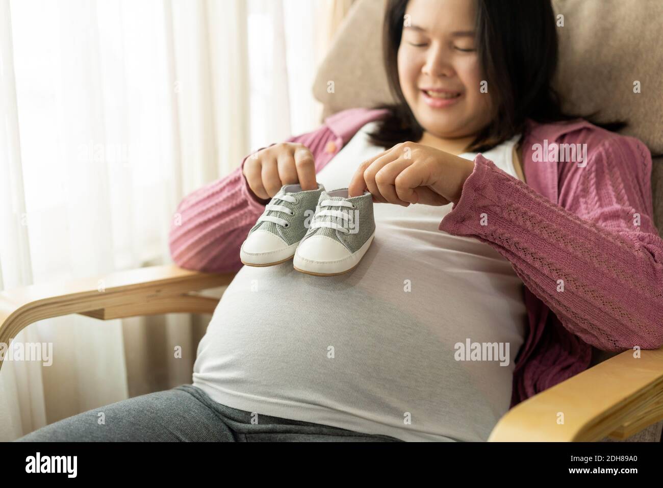 Donna incinta che si sente felice a casa mentre si prende cura del suo bambino. La giovane madre in attesa di tenere il bambino in pancia incinta. Maternità prenatale Foto Stock