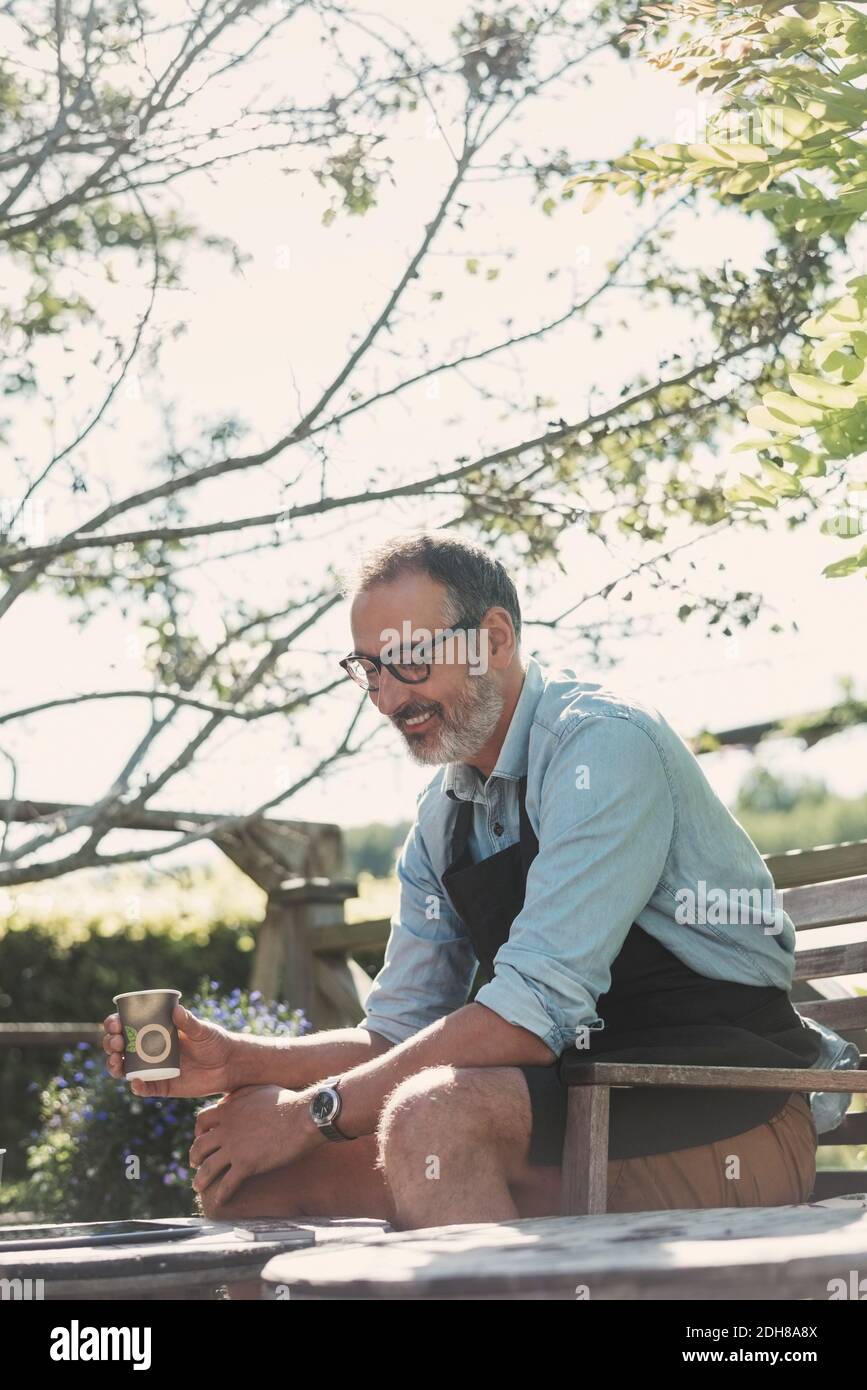Felice uomo maturo con tazza di caffè seduto in giardino Foto Stock