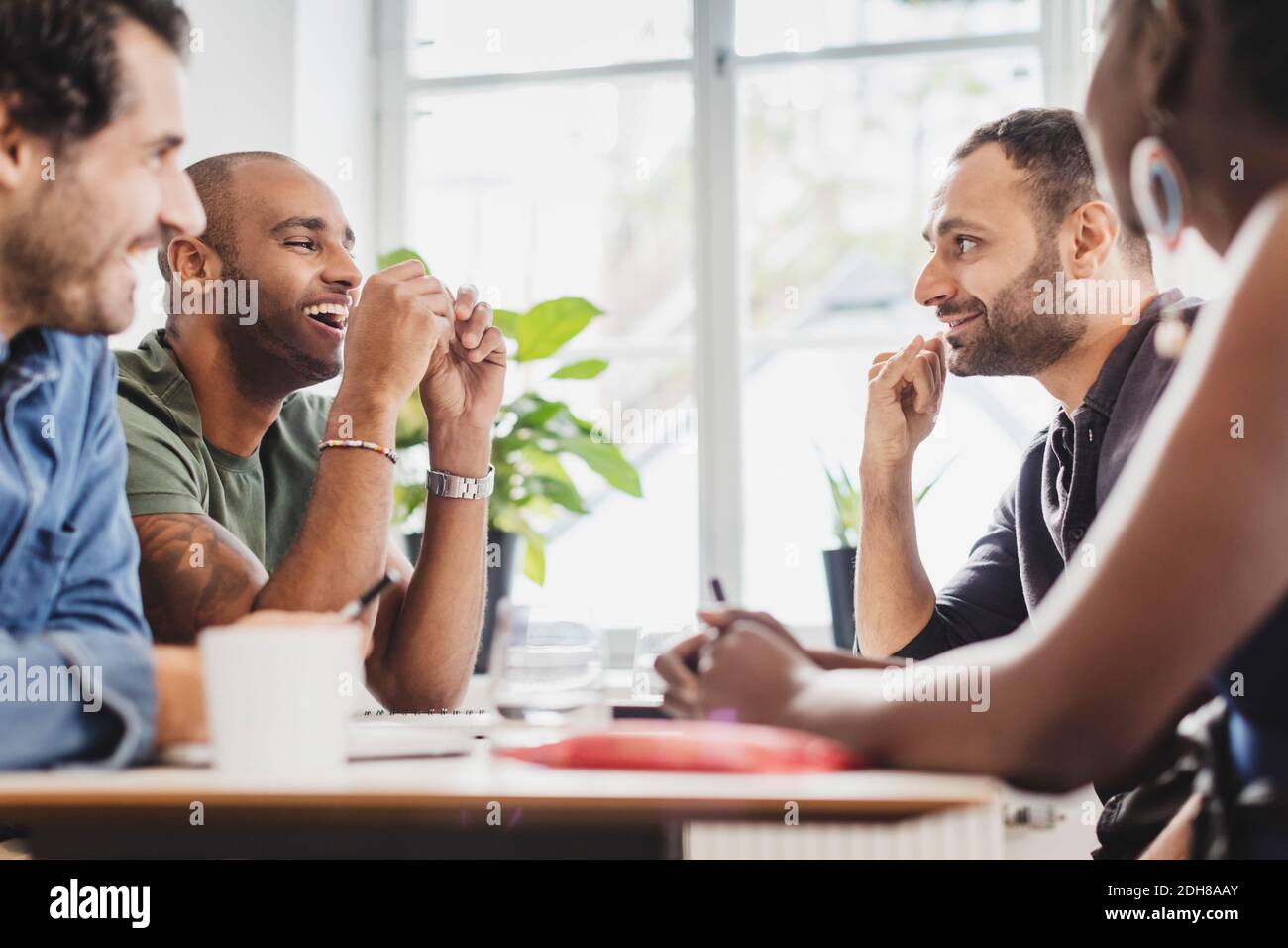 Sorridente amici seduti al tavolo in classe di lingua Foto Stock