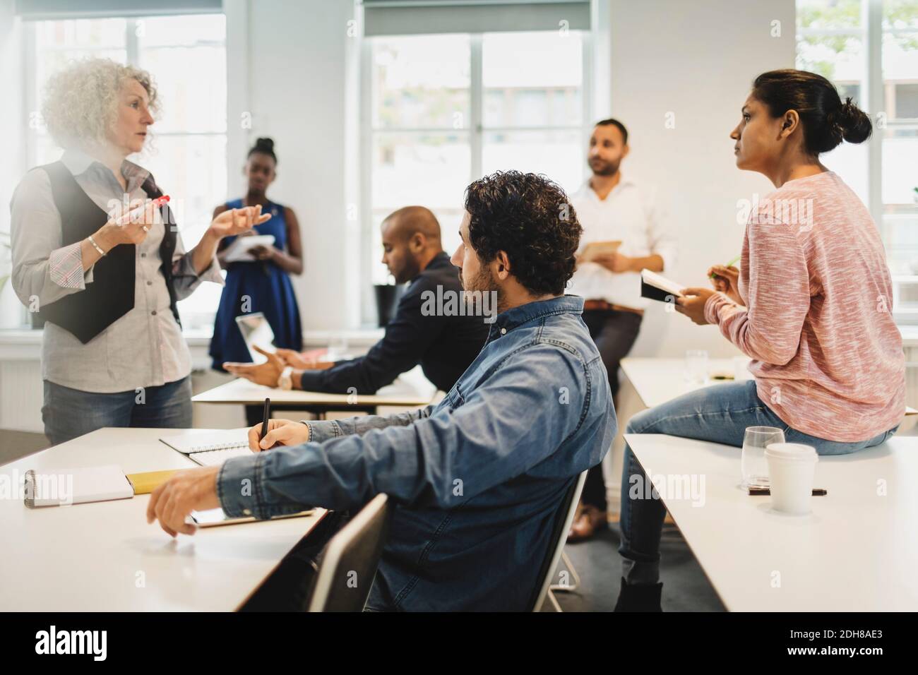 Gli studenti scrivono mentre l'insegnante spiega in classe di lingua Foto Stock