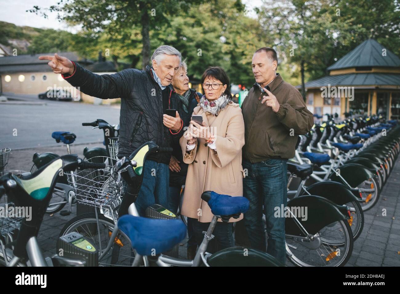 Coppie senior che utilizzano telefoni cellulari presso il parcheggio per biciclette Foto Stock