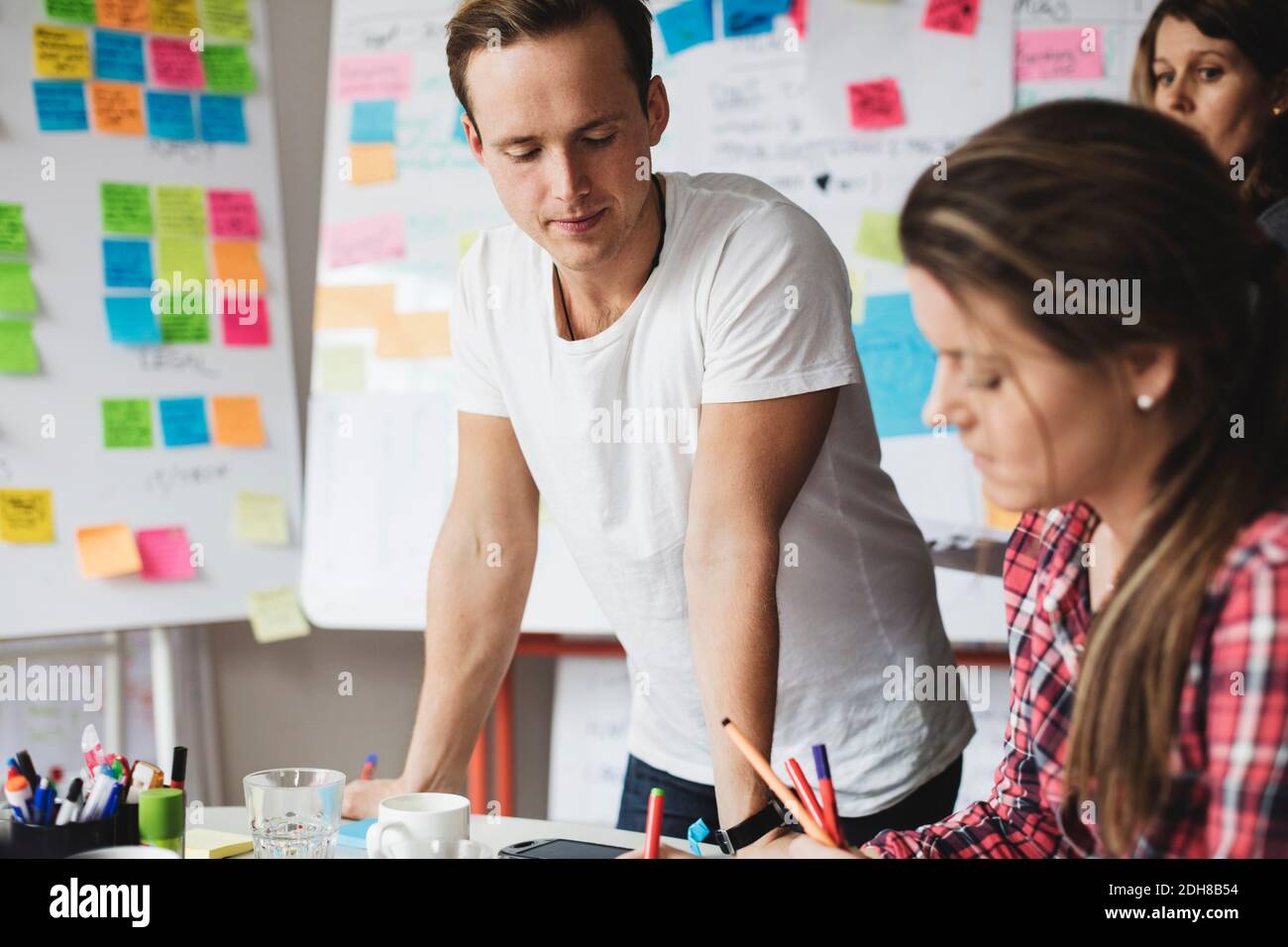 Uomo d'affari che guarda il lavoro del collega sul tavolo in creativo ufficio Foto Stock