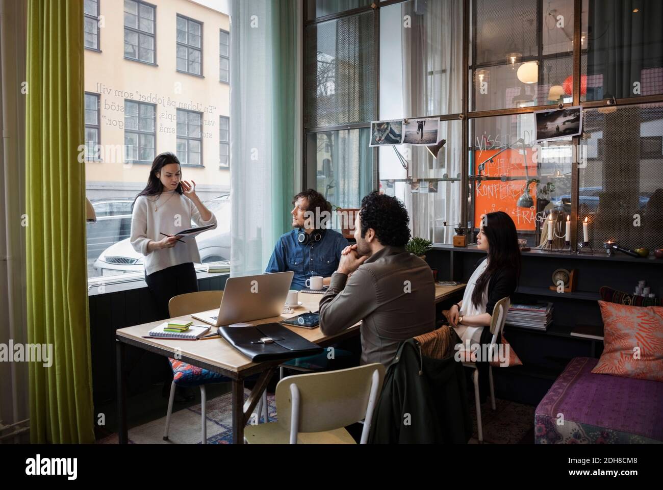 Donna d'affari creativa che condivide idee con il team in un ufficio moderno Foto Stock