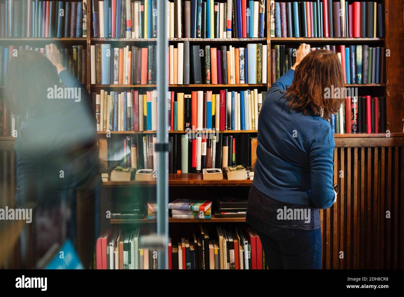 Vista posteriore della libreria che dispone libri su scaffale in antico negozio Foto Stock