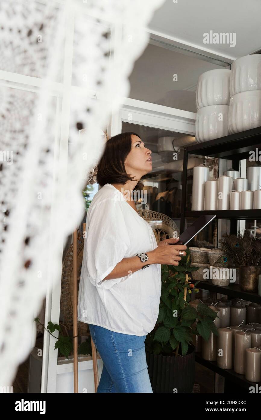 Donna proprietaria che utilizza un tablet digitale durante l'analisi degli oggetti in negozio Foto Stock