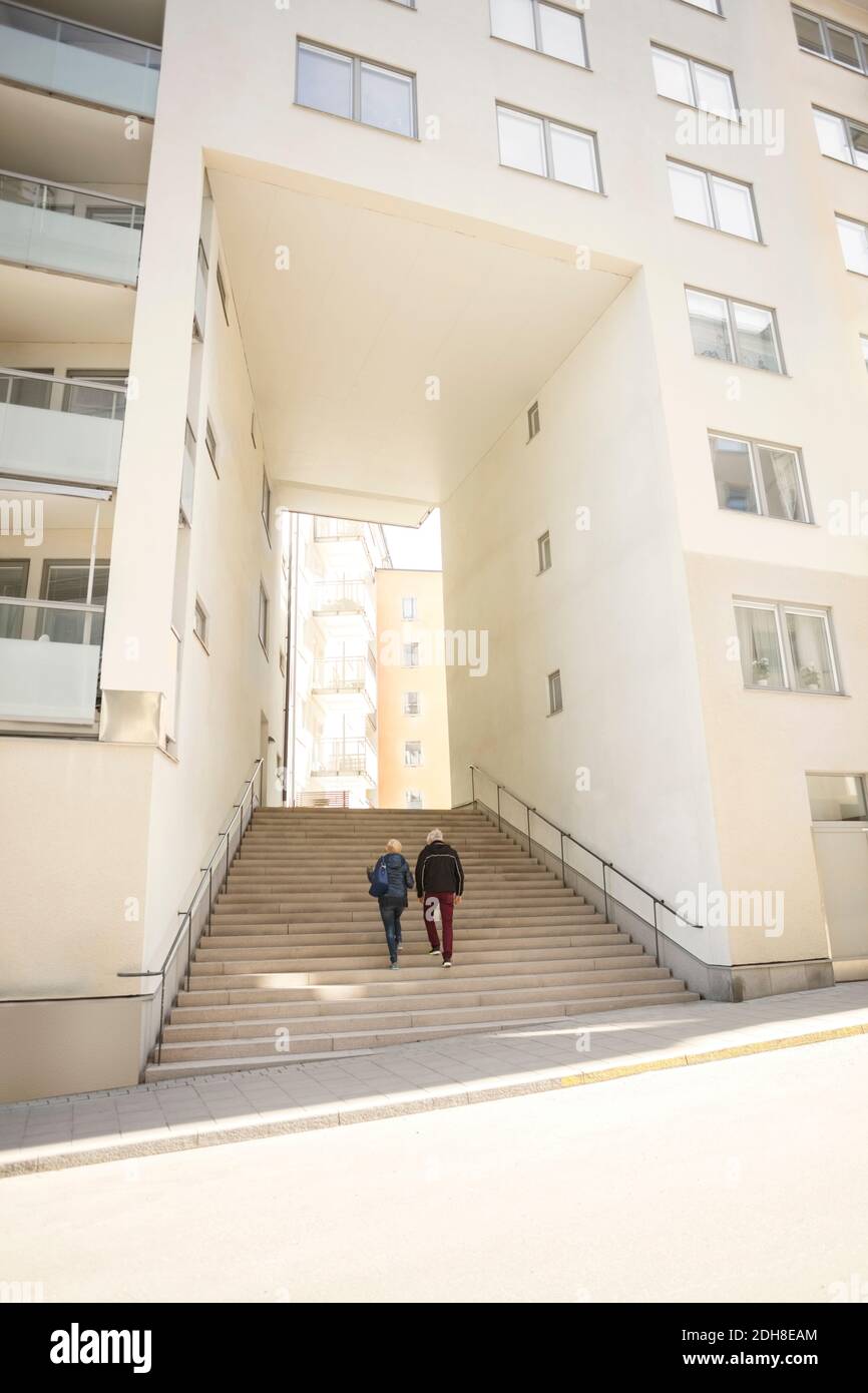 Coppia camminando su gradini che conducono all'ingresso dell'edificio Foto Stock