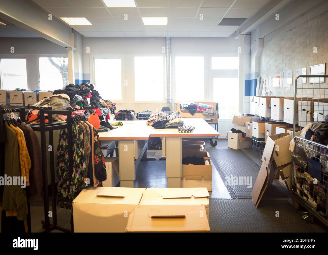 Vari abiti e oggetti con scatole in un'officina luminosa Foto Stock