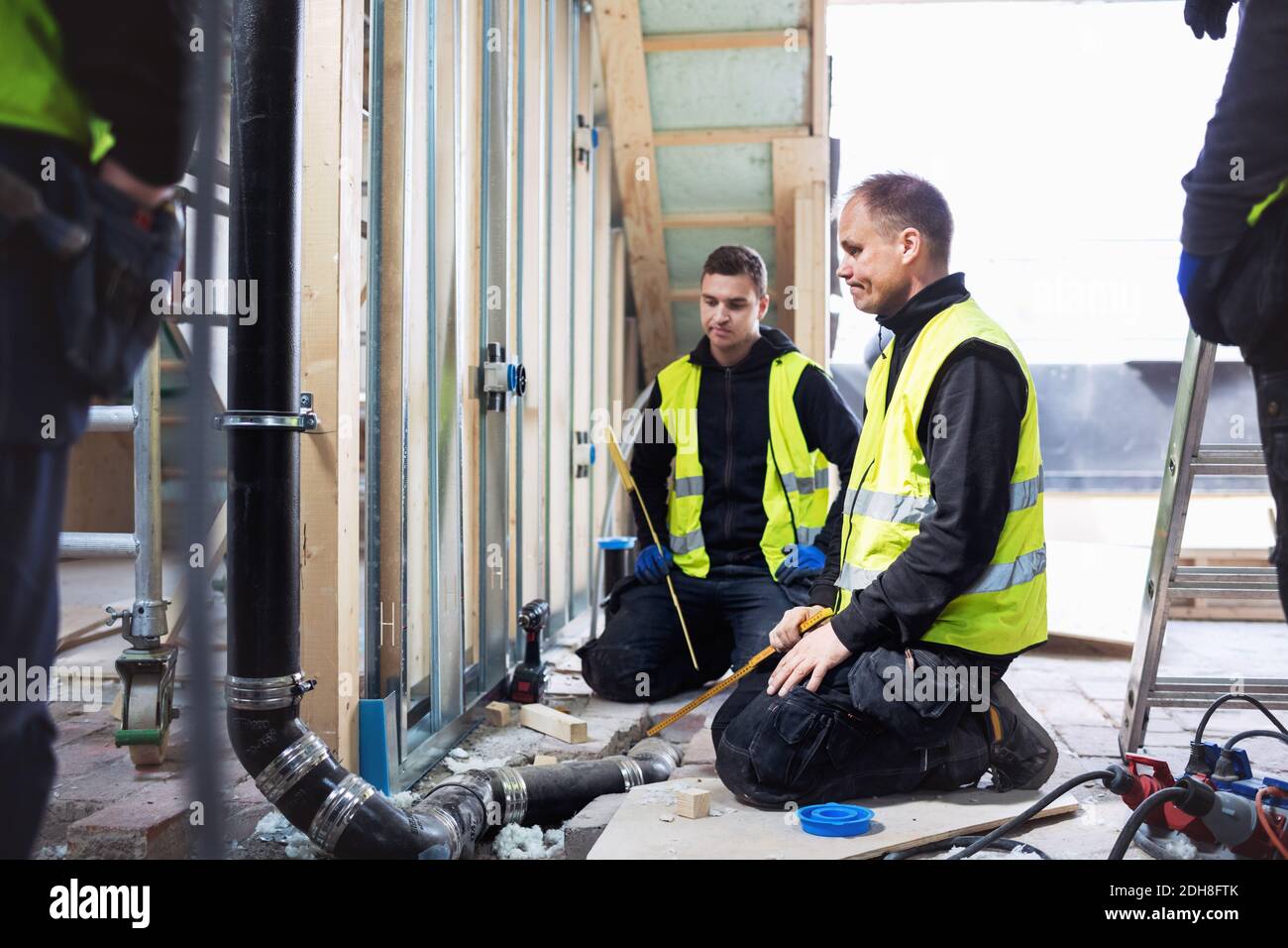 Operatori manuali premurosi che guardano il tubo mentre lavorano in costruzione sito Foto Stock